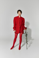 Bold red fashion statement by a young woman holding a rose in a minimalist setting
