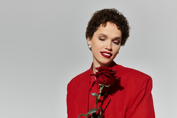 Elegant young woman with a rose exuding confidence in a striking red outfit