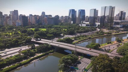 aerial view of Sao Paulo city in Brazil with a park, buildings, and Pinheiros river crossing the city. Marginal Pinheiros avenue with traffic during daylight