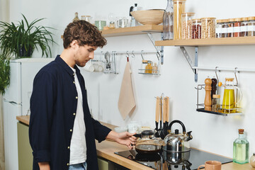 A handsome young man prepares coffee in his elegant kitchen, enjoying the cozy atmosphere.