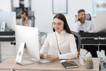 Saleswoman talking to client via headset at desk in office