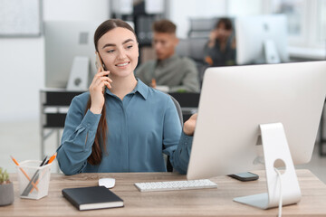 Fototapeta premium Saleswoman talking on phone at desk in office