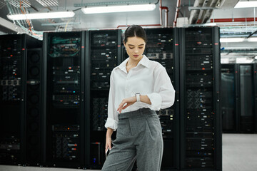 Focused woman in a white shirt manages server systems in a state-of-the-art data center.