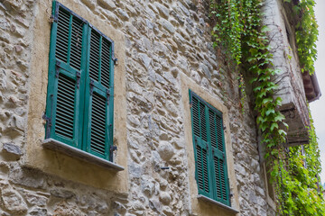 Ancient stone wall with windows covered with wooden exterior shutters