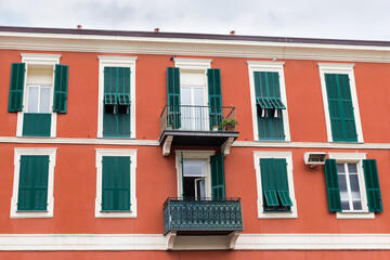 Obraz premium Red building with windows and balconies with wooden exterior shutters