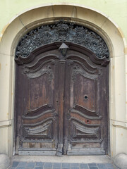 Ancient arched wooden outer door painted dark with carved ornament