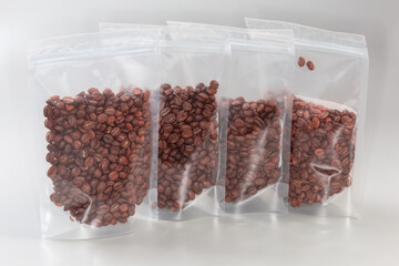 Roasted coffee beans in plastic zipper bags on gray surface