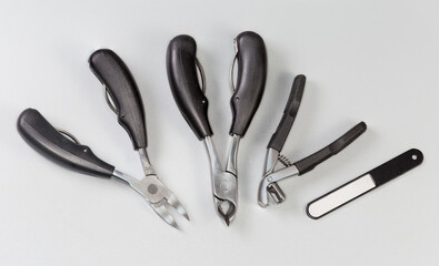 Professional stainless steel pedicure tools on gray background, top view
