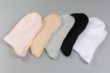 Several pairs of the women's socks different colors on gray surface