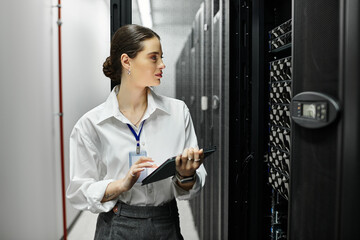 An IT specialist in a white shirt manages equipment in a data center while monitoring performance.