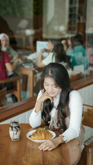 Beautiful Asian Girl, coffee shop customer staring at the food in a coffee shop.