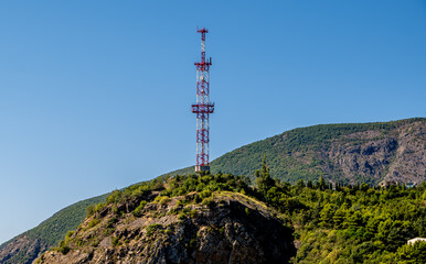 A communications tower on a hill against the sky.