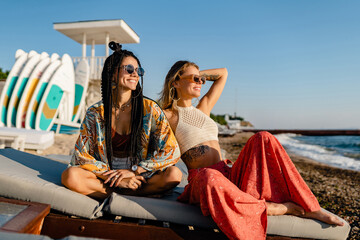two stylish beautiful women relaxing having fun on beach in summer fashion trend outfit