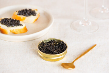 Black caviar in the gold jar with spoon, glasses of champagne and toasts on the table. Sturgeon caviar.