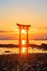Naklejka premium 冬の永尾剱神社の鳥居と夕日 干潮時 熊本県宇城市 Einoo Tsurugi Shrine torii gate and sunset in winter. At low tide. Kumamoto Pref, Uki City.