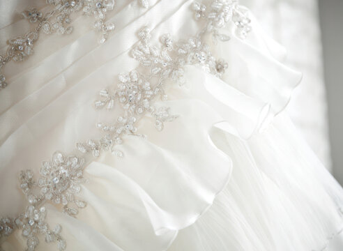 Close up of elegant white wedding dress with floral embroidery and ruffles