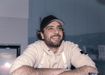 Smiling young caucasian male chef in kitchen with cap and apron
