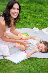 Mother playing with lying girl on green lawn