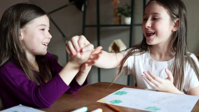 children girls playing Roshambo - Rock paper scissors at home at the table. kids games and fun