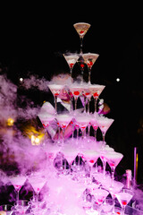 Bartender preparing a champagne tower with dry ice and cherries at an elegant party