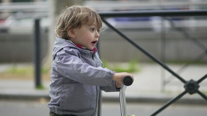 Cute little baby toddler riding scooter outside in street