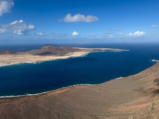 Obraz premium Breathtaking view from above from Mirador del Rio view point of Atlantic ocean, volcanic landscape and La Graciosa island on sunny day
