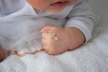 The baby is dressed in a white dress and lies with a bunny, a chain with a cross. Baptism of a child