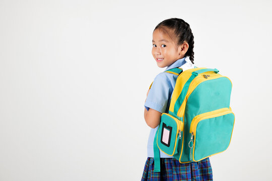Portrait Back Asian smiling young girl kids kindergarten holding a green and yellow backpack studio shot isolated white background, happy cute little schoolgirl wears school uniform, back to school