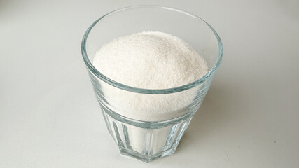 A clear glass filled with fine white sugar, symbolizing the health concerns of high sugar consumption during Halloween treats