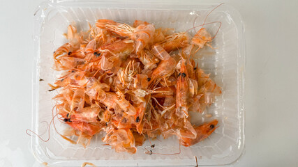 A pile of shrimp shells in a plastic container highlighting food waste and sustainability challenges during seafood feasts