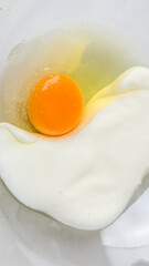 A close-up of a raw egg in a bowl, symbolizing cooking preparation and food freshness for Easter breakfast