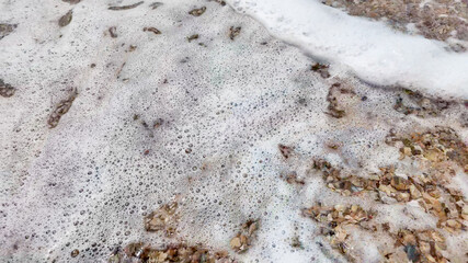Foamy ocean waves gently wash over pebbled beach, representing the concept of tranquility and environmental awareness on Earth Day