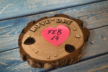 Creative concept, message on a log “Love day” with a heart written “Feb 14”.