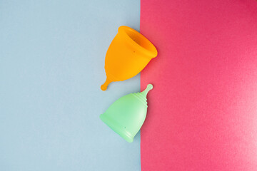 Two menstrual cups on a blue and pink background. Flat lay, top view.