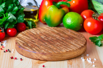 Food cooking background with round wood board, vegetables, herbs, olive oil, spice grinder, modern classic white kitchen