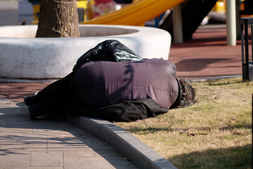 Rear view of homeless elder people lying on the street and falling asleep in sunny winter day in Shanghai, China.