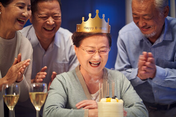 senior asian woman celebrating birthday with group of friends at home
