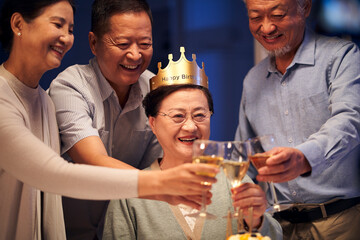 happy senior asian woman celebrating birthday with group of old friends