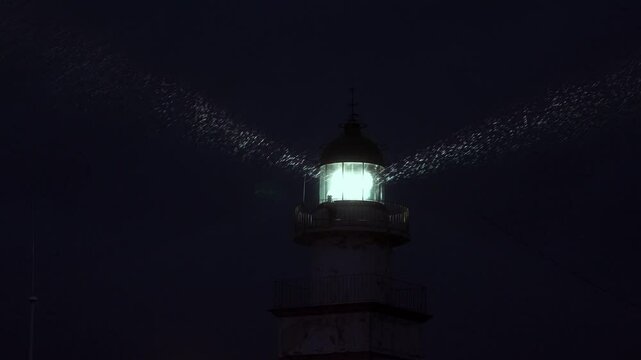 Faro iluminando mientras llueve a c&aacute;mara lenta