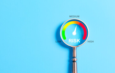Business Risk Assessment and Management Concept. A magnifying glass highlighting a risk level gauge...