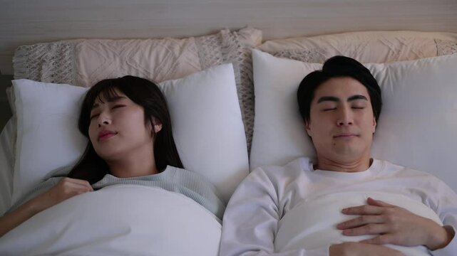 ベッドで眠る日本人の男女