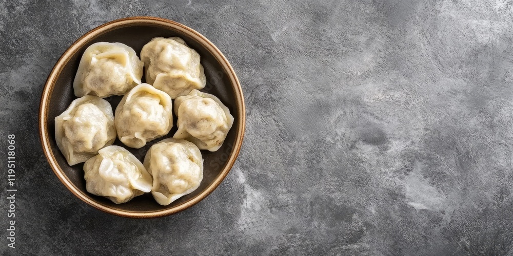 Poster cooked khinkali in a brown bowl on a textured gray stone surface with ample empty space for text on 