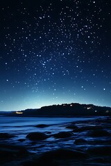 Night sky over a dark ocean and rocky shore.