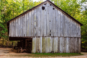 A large, old barn with a wheelbarrow in front of it
