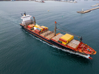 Aerial drone view of a red cargo ship loaded with containers, sailing through the Black Sea near...