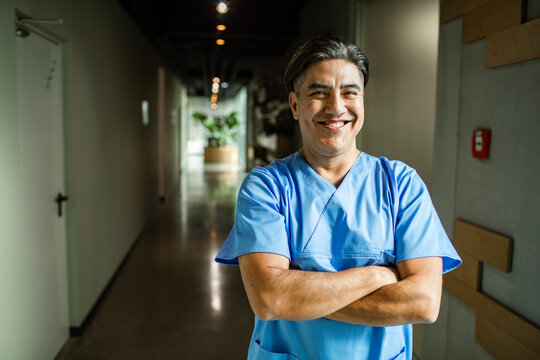 Smiling portrait of a male nurse standing confidently in hospital hallway