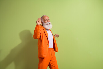 Photo of funny showman dance empty space wear orange suit isolated on green color background