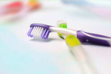 Two colorful modern manual hand toothbrushes lie on a sink or washbasin in a bathroom.	