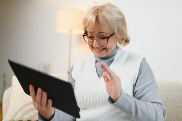 Old happy woman having a video call with her family on a tablet