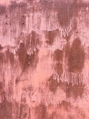 Rusty metal surface showing layers of pink paint and corrosion
